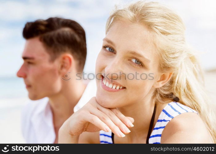 Romantic young couple sitting on the beach. Romantic young couple sitting on the beach looking at each other