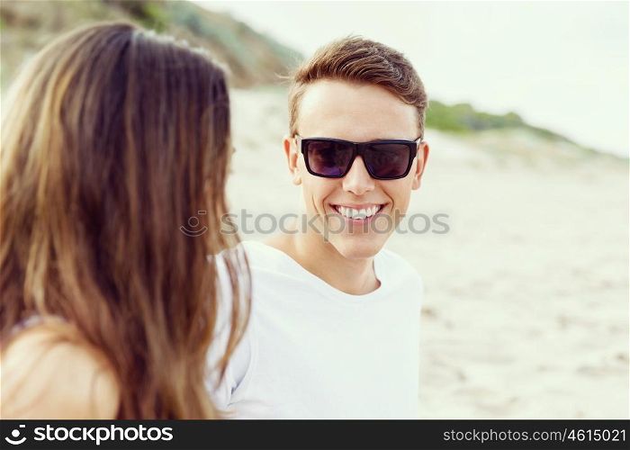 Romantic young couple sitting on the beach. Romantic young couple sitting on the beach looking at each other