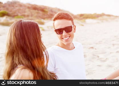 Romantic young couple sitting on the beach. Romantic young couple sitting on the beach looking at each other