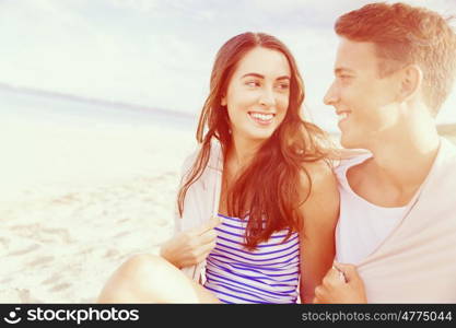 Romantic young couple sitting on the beach. Romantic young couple sitting on the beach looking at each other