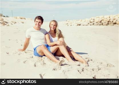 Romantic young couple sitting on the beach. Romantic young couple sitting on the beach looking at the ocean