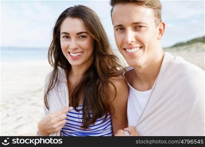 Romantic young couple sitting on the beach. Romantic young couple sitting on the beach looking at camera