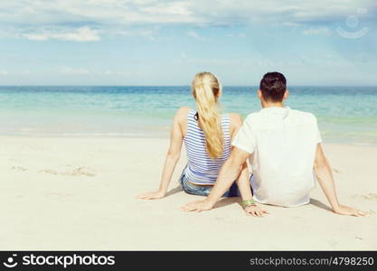 Romantic young couple sitting on the beach. Romantic young couple sitting on the beach looking at the ocean