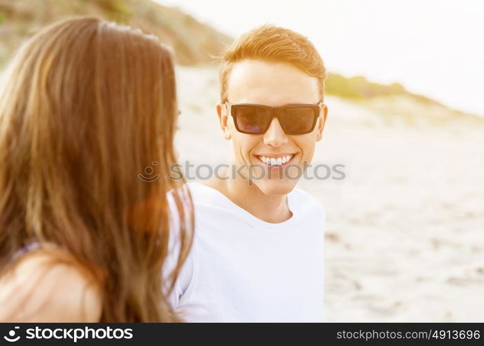 Romantic young couple sitting on the beach. Romantic young couple sitting on the beach looking at each other