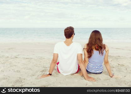 Romantic young couple sitting on the beach. Romantic young couple sitting on the beach looking at the ocean