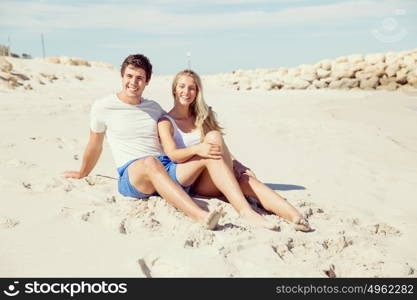 Romantic young couple sitting on the beach. Romantic young couple sitting on the beach looking at the ocean