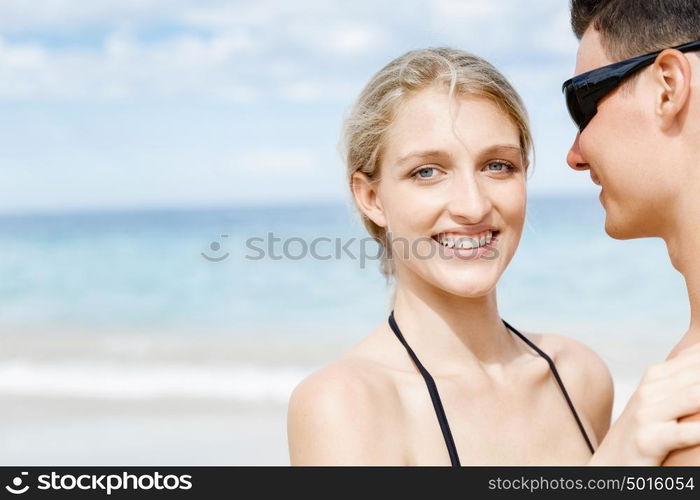 Romantic young couple sitting on the beach. Romantic young couple sitting on the beach looking at camera