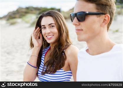 Romantic young couple sitting on the beach. Romantic young couple sitting on the beach . Girl looking at camera