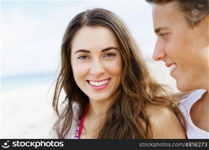 Romantic young couple sitting on the beach. Romantic young couple sitting on the beach. Girl looking at camera