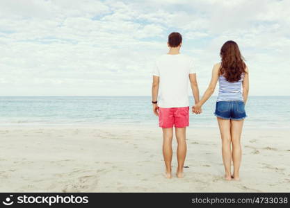 Romantic young couple standing on the beach. Romantic young couple standing on the beach looking at the ocean