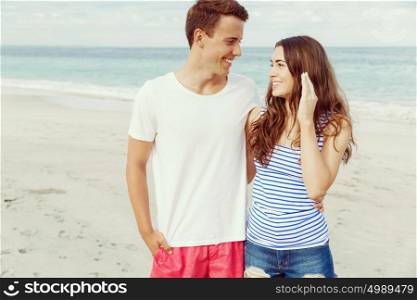 Romantic young couple standing on the beach. Romantic young couple standing on the beach looking at each other