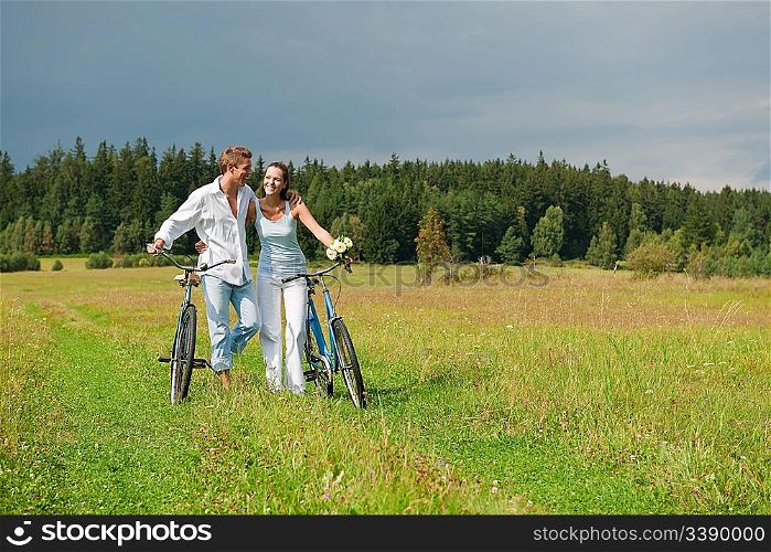 Romantic young couple with old bike in spring nature on sunny day