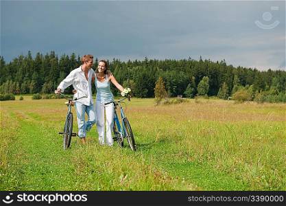 Romantic young couple with old bike in spring nature on sunny day