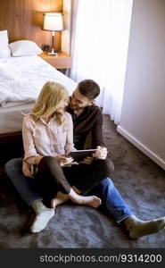 Romantic young happy couple in love sitting on floor resting and  having fun surfing internet