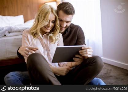 Romantic young happy couple in love sitting on floor resting and  having fun surfing internet