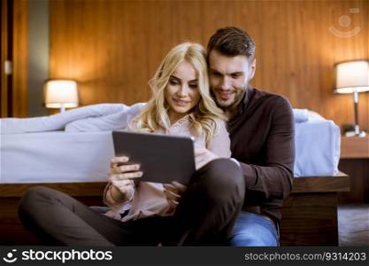 Romantic young happy couple in love sitting on floor resting and  having fun surfing internet