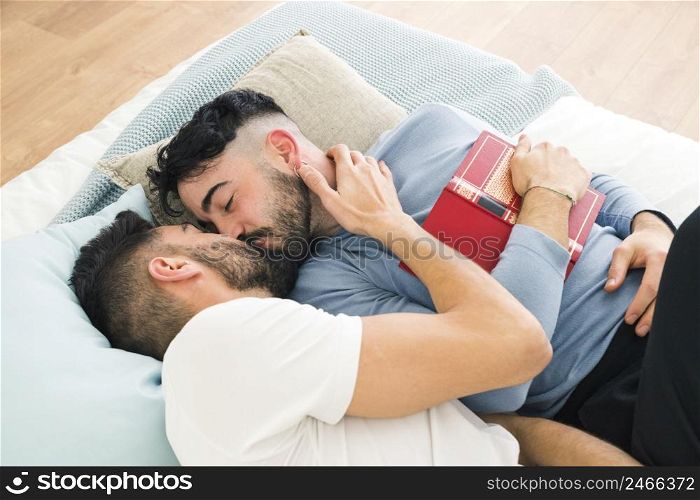 romantic young homosexual couple lying bed kissing