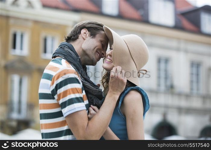 Romantic young man kissing woman against buildings