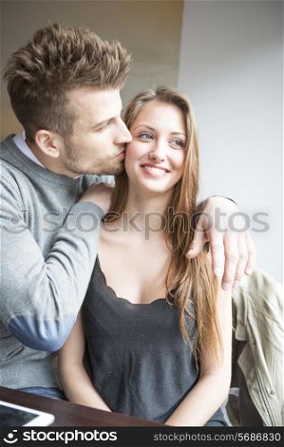 Romantic young man kissing woman in cafe