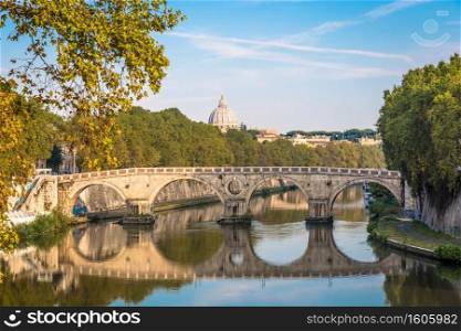 ROME, ITALY - CIRCA AUGUST 2020  Bridge on Tiber river with Vatican Basilica cupola in background and sunrise light.