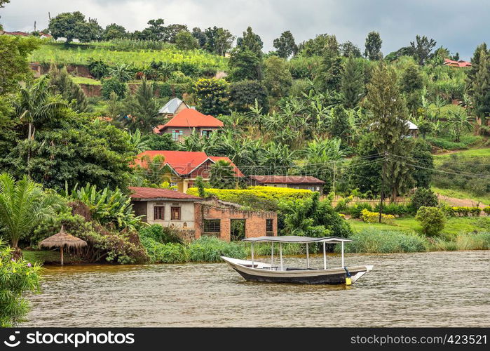 Roof boat anchored at the coast with rwandan village in the background, Kivu lake, Rwanda