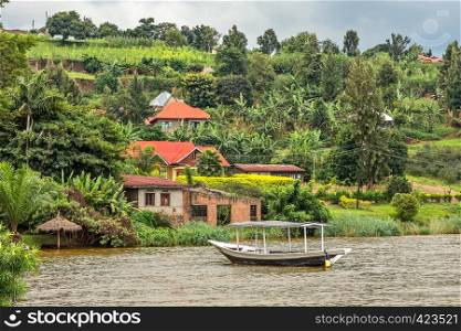 Roof boat anchored at the coast with rwandan village in the background, Kivu lake, Rwanda