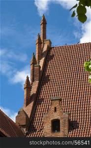 Roof tiles and decorations of a building in the middle replaced in Malbork. Poland