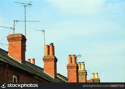 Roof tops and brick chimneys on house in typical english town, blue sky