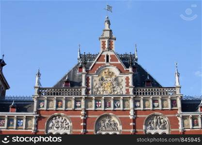 Rooftop details of Amsterdam Central Station with coat of arms, emblems, reliefs in Holland, Netherlands.