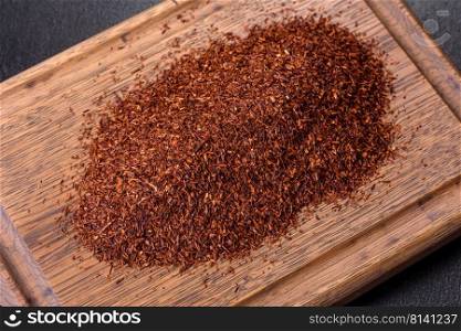 Rooibos tea in a white bowl on a black background. Flat lay, top view, copy space. Rooibos tea on a black background. Flat lay, copy space