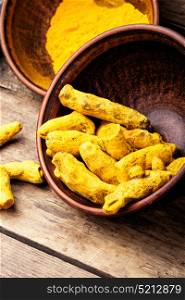 Roots and turmeric powder. Turmeric powder and root turmeric in a bowl.Turmeric Spice