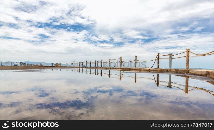 Rope fence along the shores of the Red sea reflecting the clouds in the sky