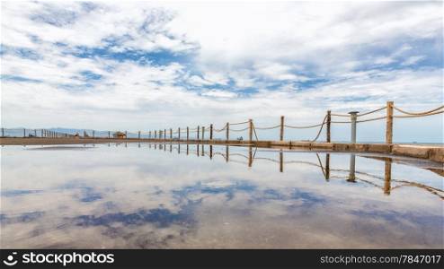 Rope fence along the shores of the Red sea reflecting the clouds in the sky