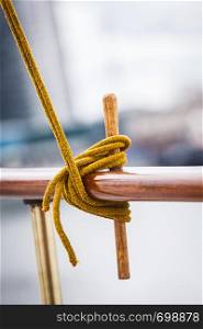 Rope tied around hook on handrail. Outdoor shot city by the water in background.. Rope tied around hook on handrail