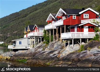 rorbuer - traditional norwegian red wooden house to stand at the lakeside and mountains in the distance, norway