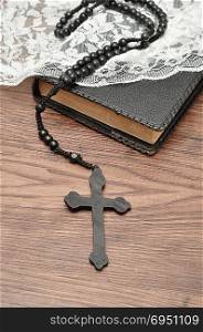 Rosary beads and a bible with a white chapel veil