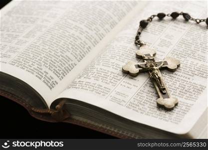 Rosary with crucifix lying on open Bible.