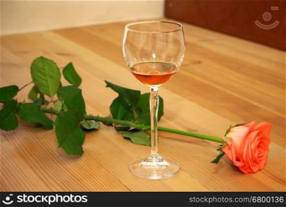 Rose and cognac on wooden floor. Element of design.