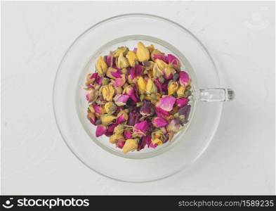 Rose buds mix tea in clear glass cup on white background. Top view