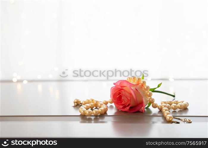 Rose fresh flower and jewellery on gray table by the window. fresh rose flowers on gray