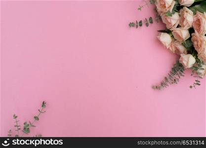 Rose fresh flowers and green leaves on pink table from above with copy space, flat lay frame. fresh rose flowers. fresh rose flowers