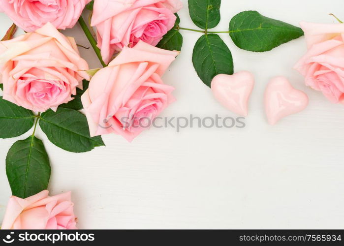 Rose fresh flowers on table from above with two hearts and copy space, flat lay scene. fresh rose flowers