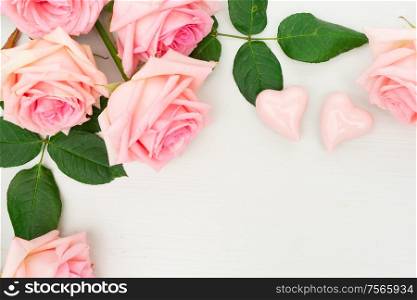 Rose fresh flowers on table from above with two hearts and copy space, flat lay scene. fresh rose flowers