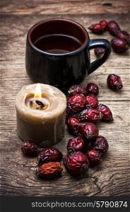 rose hips. mug of tea and dried berries of the wild rose on wooden table in rustic style