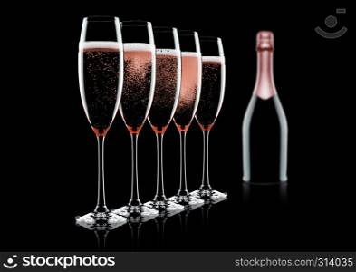 Rose pink champagne glasses and bottle on black background with reflection