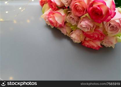Rose pink flowers bouquet with jewellery on gray table from above, flat lay scene. fresh rose flowers on gray