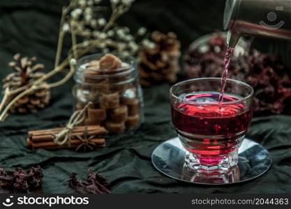 Roselle tea (Jamaica sorrel, Rozelle or hibiscus sabdariffa ) is poured from a kettle into glass cup with dry roselle and brown cane sugar cube. Healthy herbal tea rich in vitamin C and minerals. The concept of health. Organic and Summer drink, Drinks & Beverages, No focus, specifically.