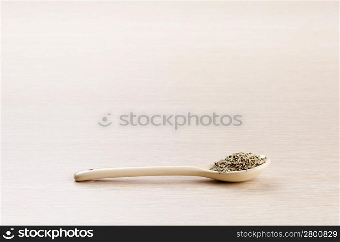 Rosemary in a spoon over a blured wooden background with copy space