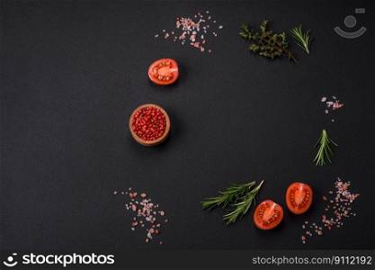 Rosemary, thyme, allspice, salt, cherry tomatoes and other spices and herbs on a dark concrete background. ingredients for cooking at home