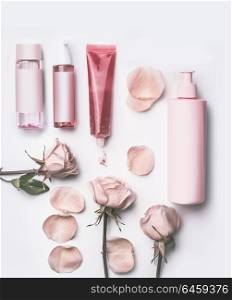 Roses cosmetic products set with fresh pink roses flowers and petals on white desktop background, top view, flat lay